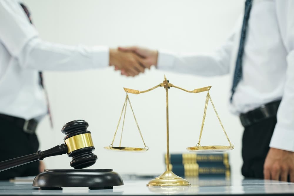 A male lawyer shakes hands with a client after a successful negotiation and cooperation meeting in the courtroom.