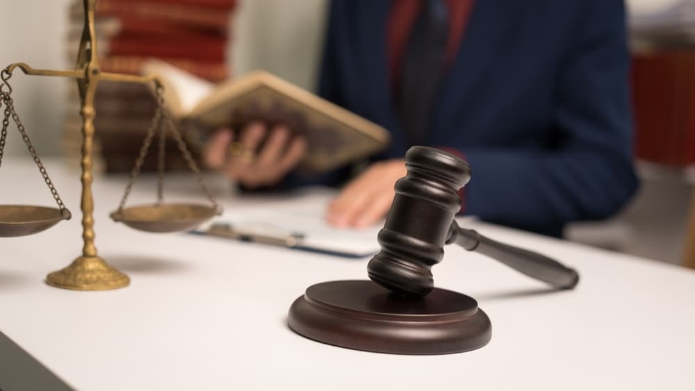 A male lawyer working with a law book, dealing with legal bindings, unilateral and multilateral contracts, obligations, power of attorney, prescription defense, and court decrees.