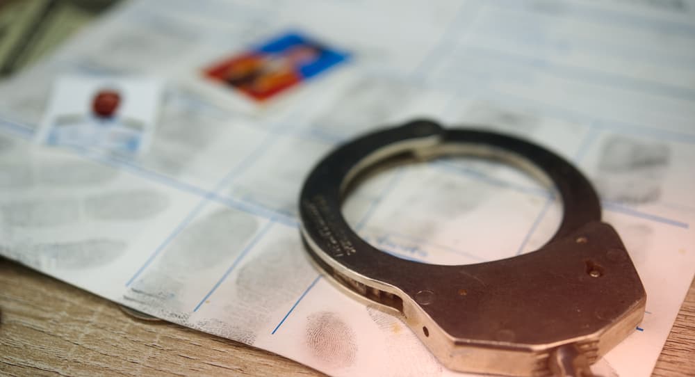 Police handcuffs placed on a crime report with fingerprint evidence.