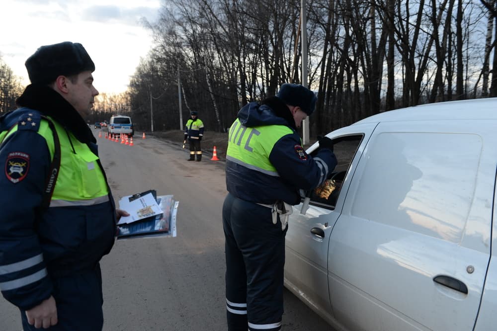 Traffic inspector in Snegiri, Russia, on March 14, 2014, conducting a roadside document check for a car driver, highlighting law enforcement duties.