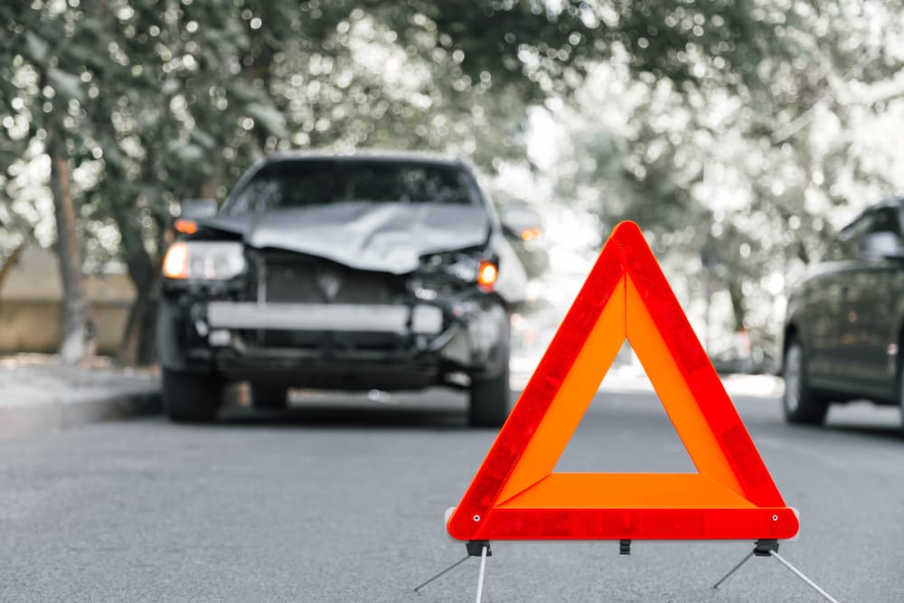 Red emergency stop triangle sign on road in a hit and run car accident scene.