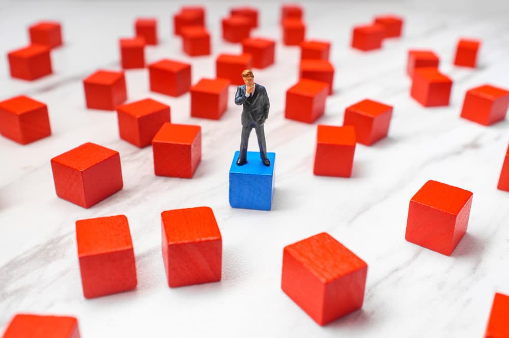 Miniature businessmen surrounded by wooden blocks, symbolizing different choices and solutions to a problem, illustrating decision-making and strategic planning.