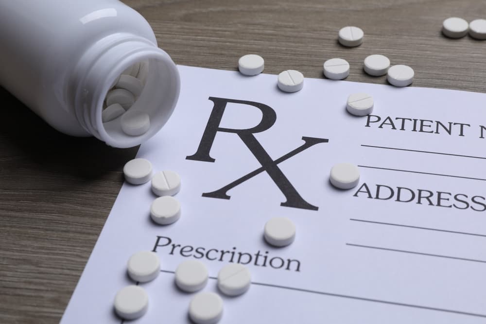 Medical prescription form, pills and bottle on wooden table