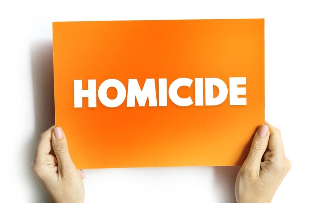 Homicide written on a banner hold by a lady