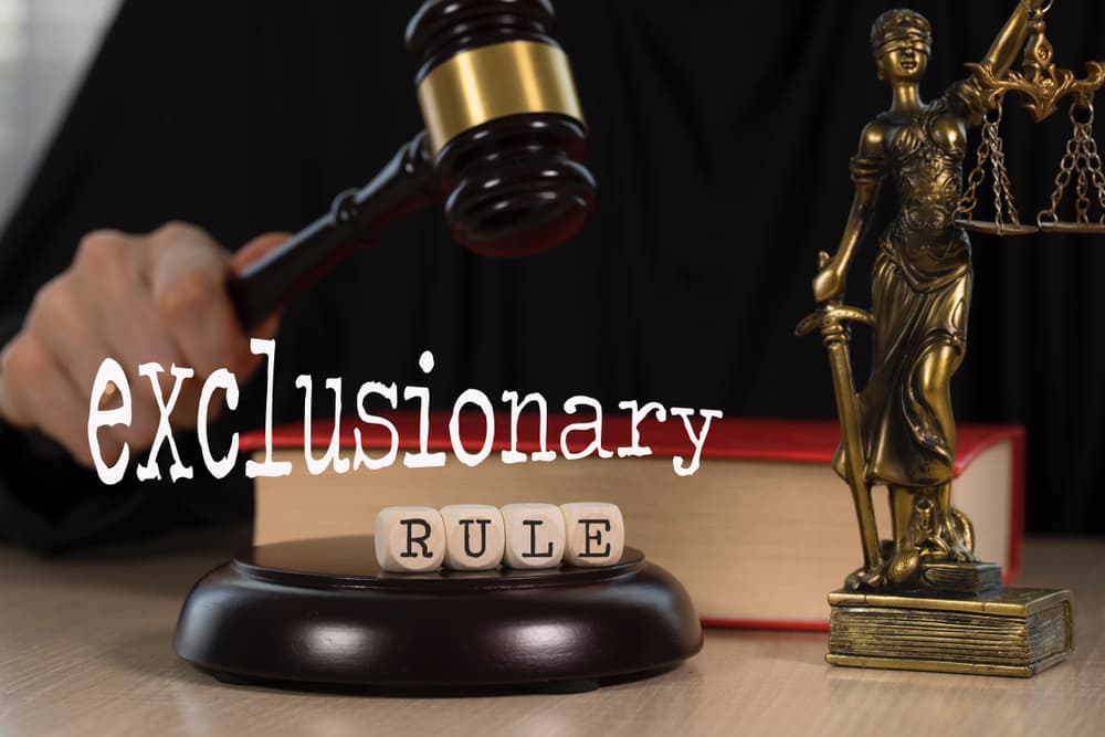 he word "EXCLUSIONARY RULE" is spelled out using wooden dice, with a wooden gavel and a statue of Themis in the background. The close-up shot highlights the legal concept, symbolizing justice and courtroom procedures related to unlawfully obtained evidence.