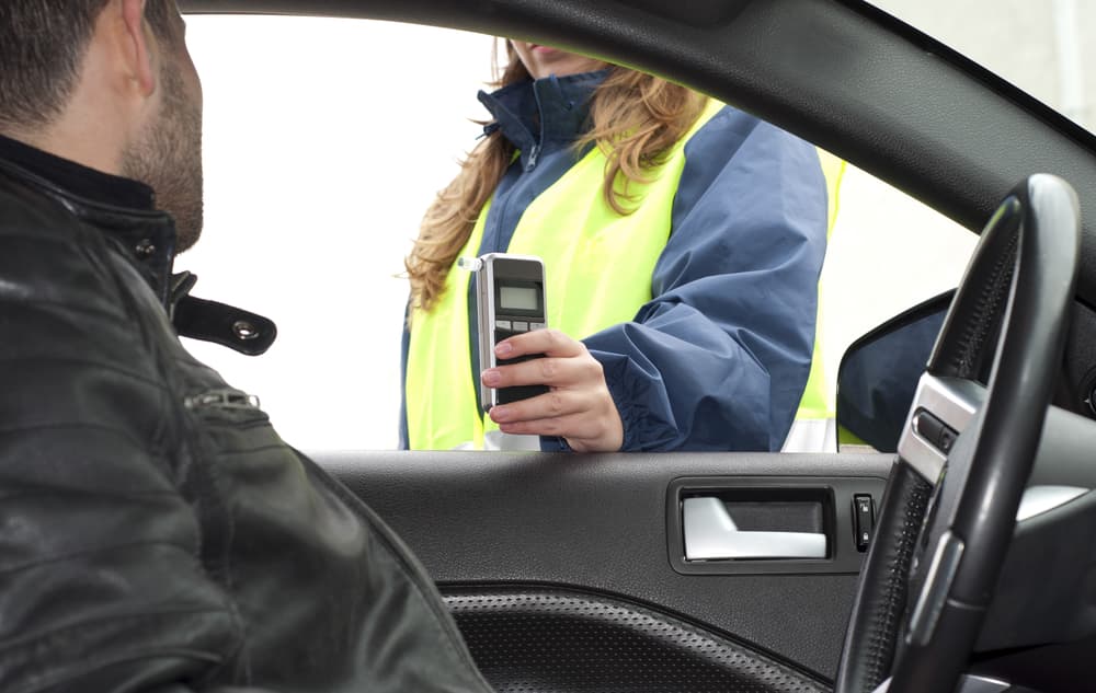 Inside the car view of a young drink and drive crashed driver due to being subject to test for alcohol content with use of breathalyzer at DWI Stop