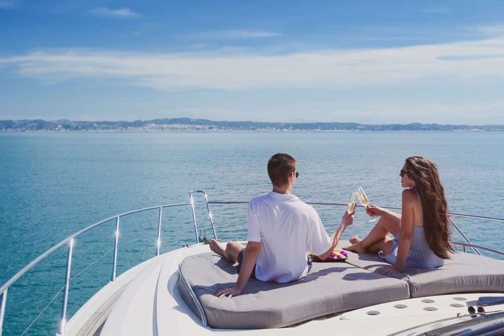 Couple drinking champagne on luxury boat, luxurious yacht cruise in tropical sea